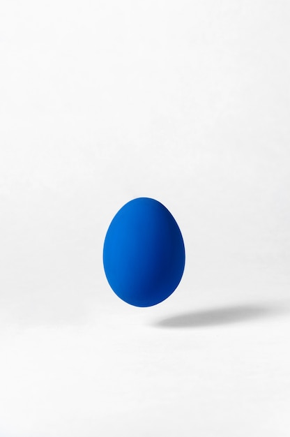 flying egg on white background. creative easter  . minimalism concept. trendy color of year - classic blue. copy space