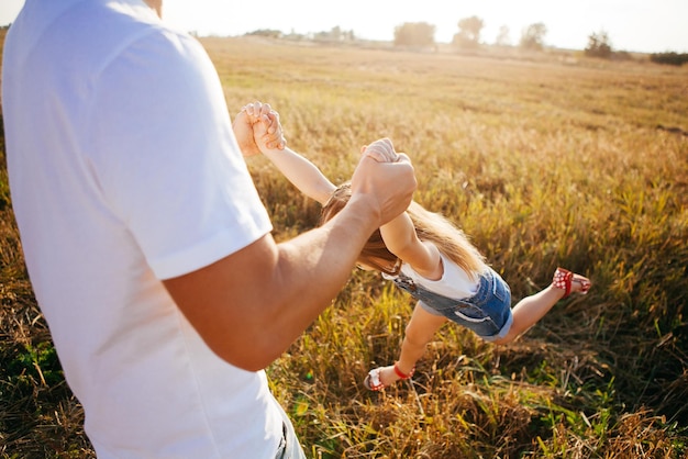 Flying girl in the arms of parents in nature