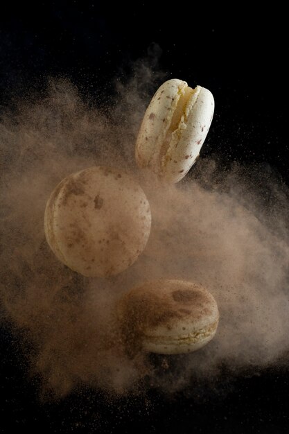 Flying macaroons on a black background, freezing in motion with cocoa.