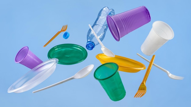 写真 青い背景に色とりどりの使い捨てプラスチック食器を飛ばすエコロジーとrの概念