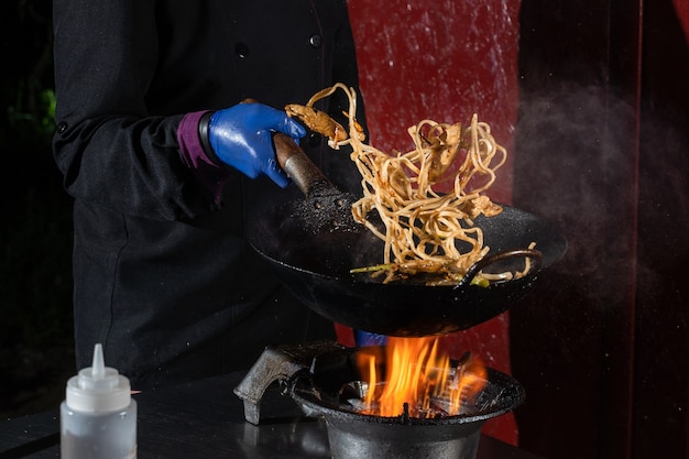 Flying noodles for wok box with meat, soy sauce fried in a wok pan, street food.