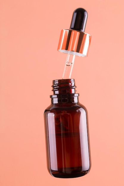 フライングは、ベージュ色の背景にピペットで茶色のスポイトガラス瓶を開いた血清酸性油