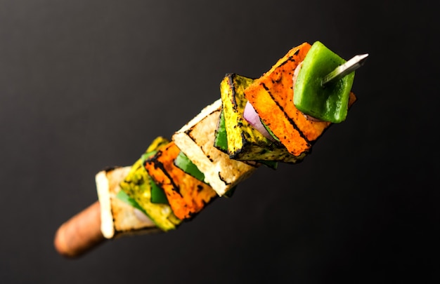 Flying Paneer Tikka isolated over black surface, selective focus