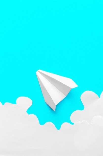 Flying paper plane in the clouds on a blue background. concept\
of flight, travel, transfer