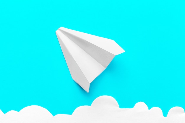 Photo flying paper plane in the clouds on blue