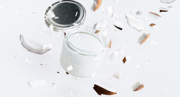 Flying pieces of coconut around coconut butter in glass jar. 