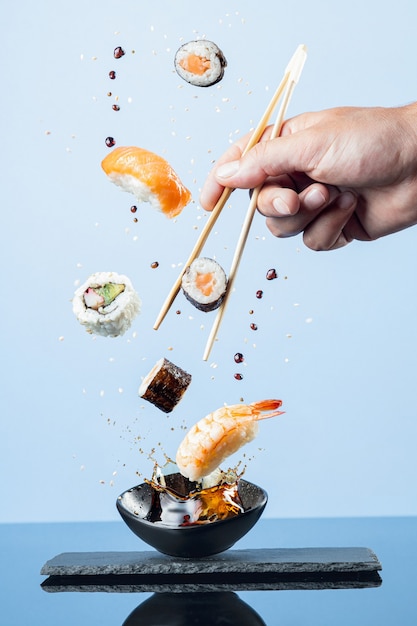 Flying pieces of sushi  on blue background.  Vertical format.