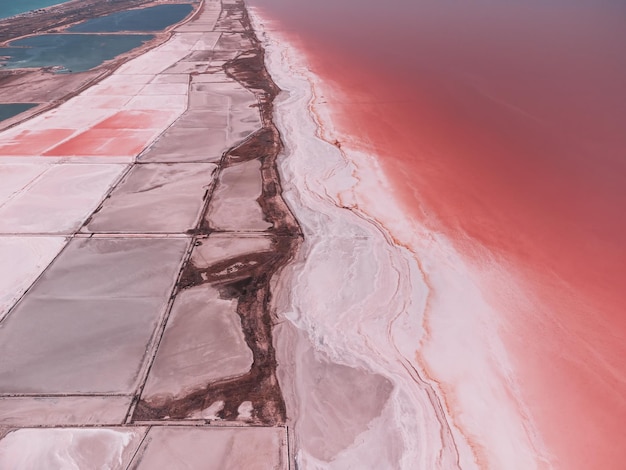 Flying over a pink salt lake Salt production facilities saline evaporation pond fields in the salty lake Dunaliella salina impart a red pink water in mineral lake with dry cristallized salty coast