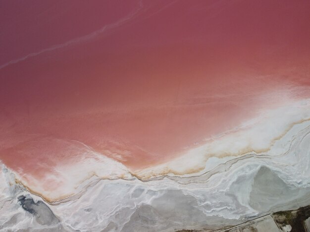 Photo flying over a pink salt lake salt production facilities saline evaporation pond fields in the salty
