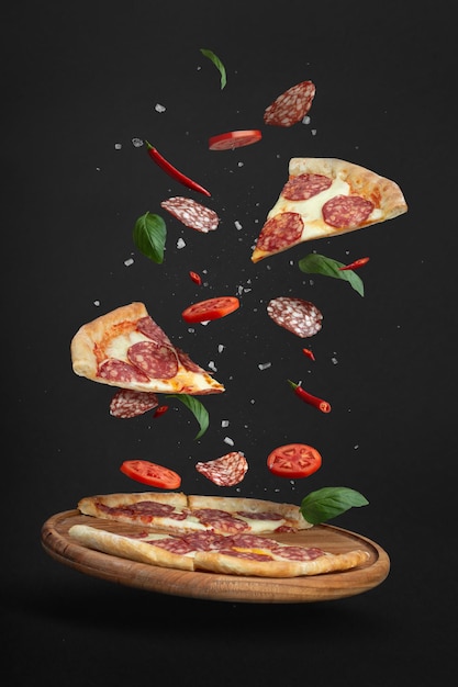 Flying pizza with ingredients on a black background