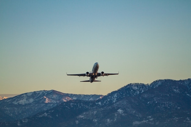 Flying plane on a surfce of blue sky and mountains