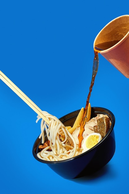 Flying ramen soup with chicken and noodles. Levitating noodles in ramen and pouring soup into a bowl