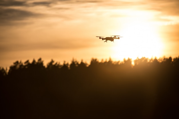 Flying silhouet van drone tegen zonsondergang. Vliegend silhouet van hommel tegen mooie zonsonderganghemel