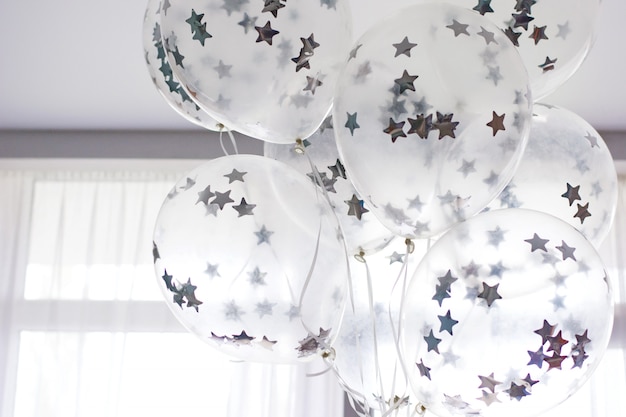 Flying white balloons with silver stars under the ceiling