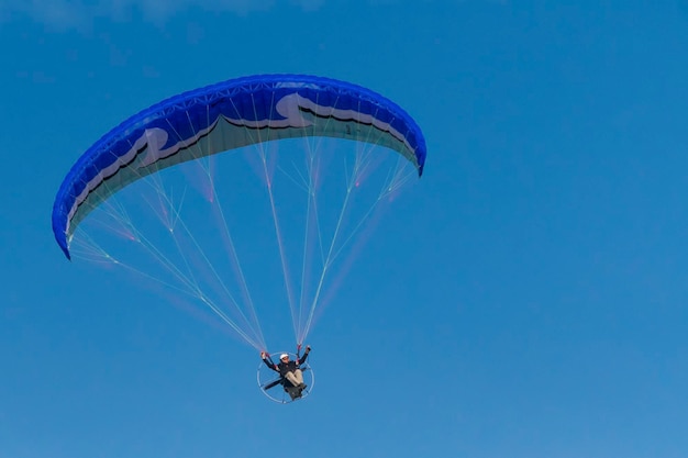 Photo flying with paramotor in the air on blue sky background