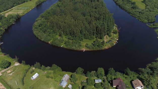 Photo flying over the wooden houses on the river shore shot aerial view of a small village and a curved