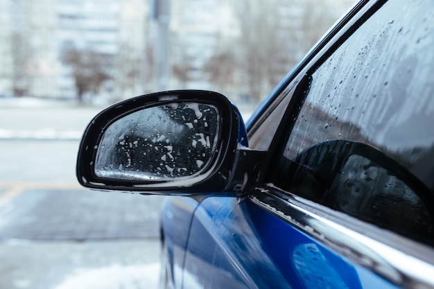 Schiuma dello shampoo per auto dietro lo specchietto laterale dell'auto. concetto di autolavaggio