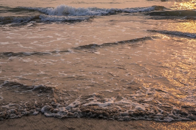 foam of sea or ocean waves against the backdrop of the setting sun
