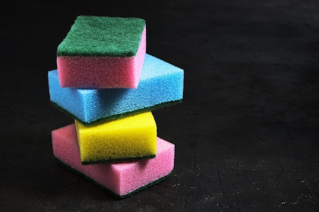 Foam sponges of different colors on a dark background.