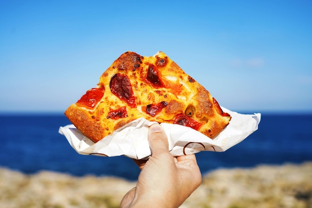 Foto fetta di focaccia barese con mare mediterraneo sullo sfondo focaccia pugliese contro il mare blu e cielo focaccia baristyle