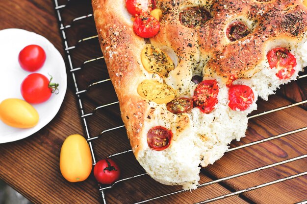 Photo focaccia. italian bread. bread with tomatoes. homemade food. cook at home. fresh bread on the wire rack