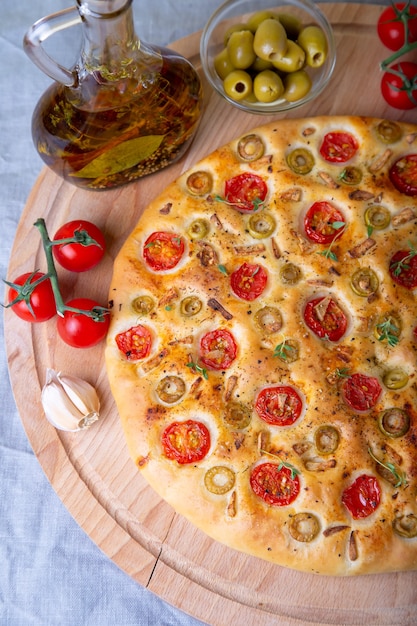 Focaccia met tomaten en olijven. Traditioneel Italiaans brood. Zelfgemaakt bakken. Close-up, selectieve aandacht.