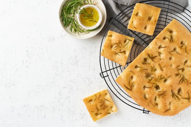 Focaccia, pizza, italian flat bread with rosemary and olive oil on grid