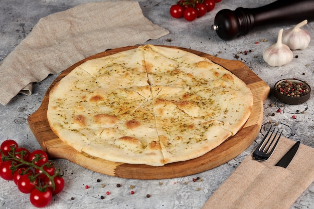 Focaccia with garlic and oregano on a wooden board, gray background