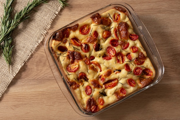 Focaccia al rosmarino, olio d'oliva e pomodoro su tavola di legno.