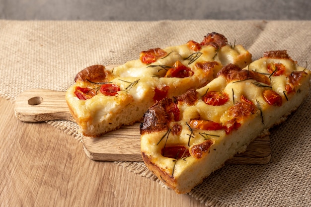 Focaccia with rosemary and olive oil and tomatoes over wooden table