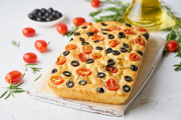 Focaccia with tomatoes, olives and rosemary. Traditional Italian flat bread