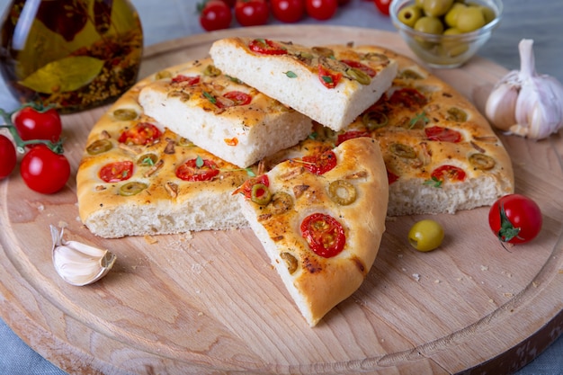 Focaccia with tomatoes and olives. Traditional Italian bread. Homemade baking. Close-up, selective focus.