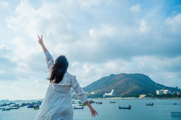 Focus achteraanzicht gelukkig Aziatisch meisje steekt haar handen op voor het strand bij Vung Tau Travel concept