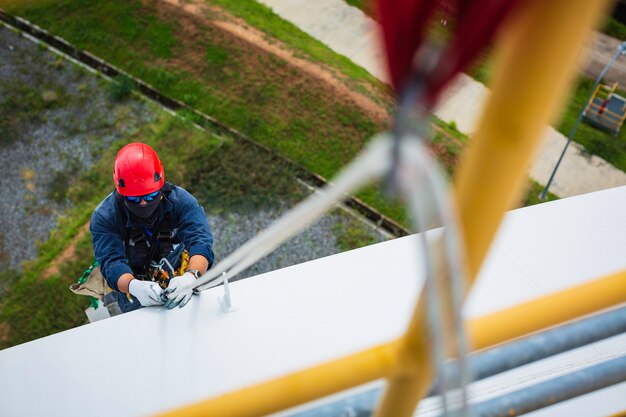 Focus bovenaanzicht mannelijke werknemer naar beneden karabijnhaak touw hoogte tank dak knoop leuning touw toegang veiligheidsinspectie van dikte opslagtank dak.