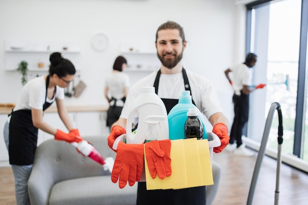 Photo focus on bucket with detergents in hands of caucasian man cleaning worker