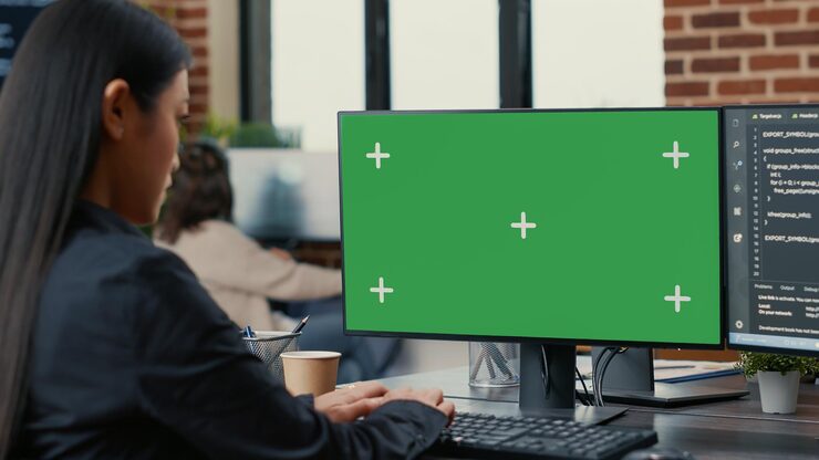 Photo focus on computer screen with green screen chroma key mockup in front of asian programer writing code in software development agency. database coder programming sitting at desk.