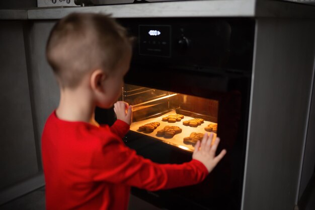 Focus on cookies in the oven a boy watches how sweets are baked\
at home in the kitchen