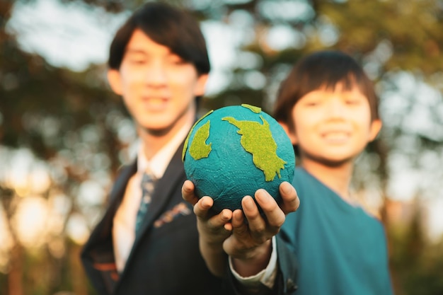 Focus Earth with blurred asian boy and businessman holding globe together Gyre