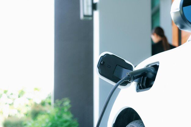 Focus EV-auto thuis laadstation met onscherpte progressieve vrouw achterin