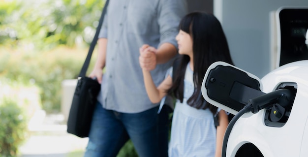 Photo focus ev car recharging battery at home with progressive people in background