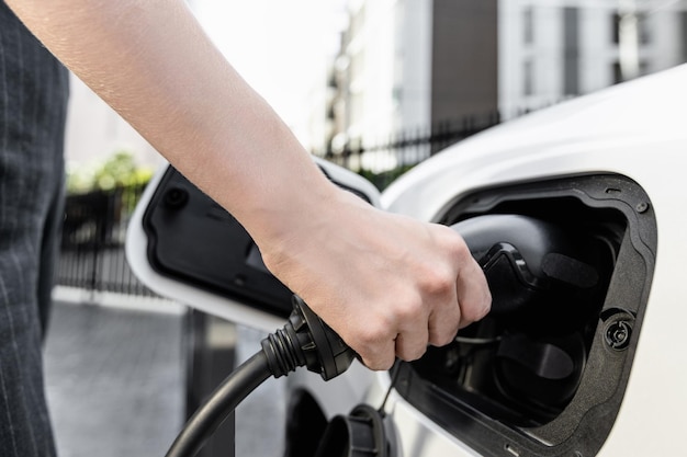 Focus EV charger plug with blur progressive woman charge EV car in background