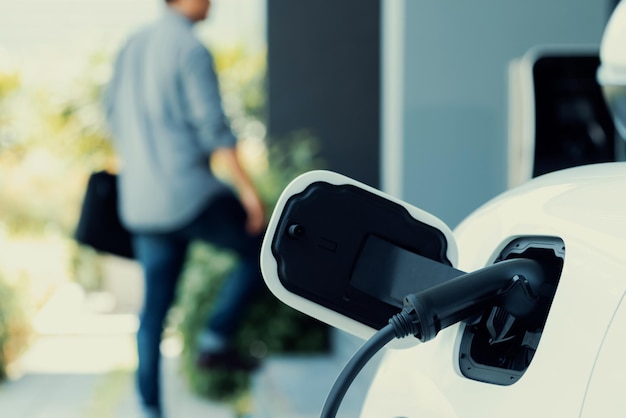 Focus EV charging station at home with blur progressive man in background