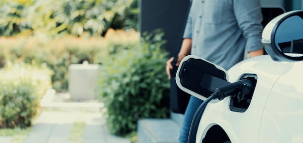 Focus EV charging station at home with blur progressive man in background