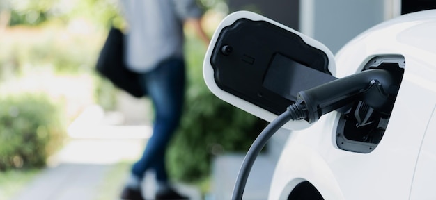 Photo focus ev charging station at home with blur progressive man in background