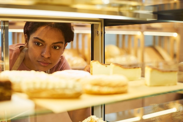 パン屋の若いアフリカ系アメリカ人の女性店員の顔に焦点を当てる