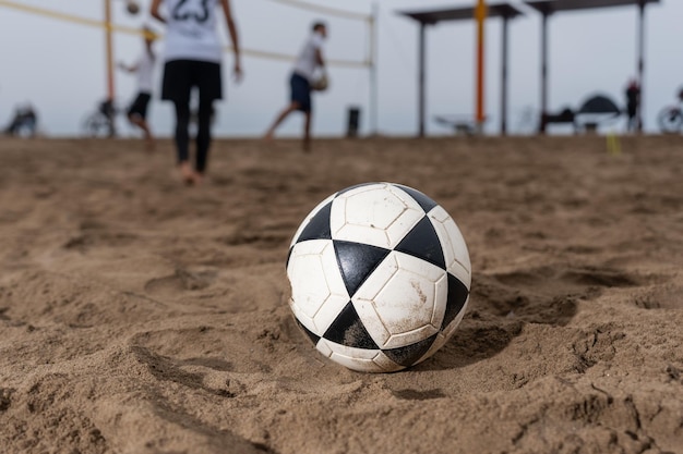 ビーチの砂でサッカー ボールに焦点を当てる