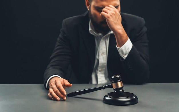 Focus gavel with blur lawyer sitting at his desk and worried equility