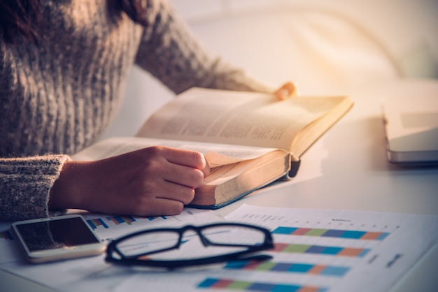 Focus hand open book for reading on desk work with gold lighting at the morning 