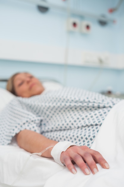 Focus on the hand of a patient lying on a medical bed