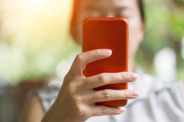 Focus hand van jonge Aziatische vrouw aanraken rode smartphone